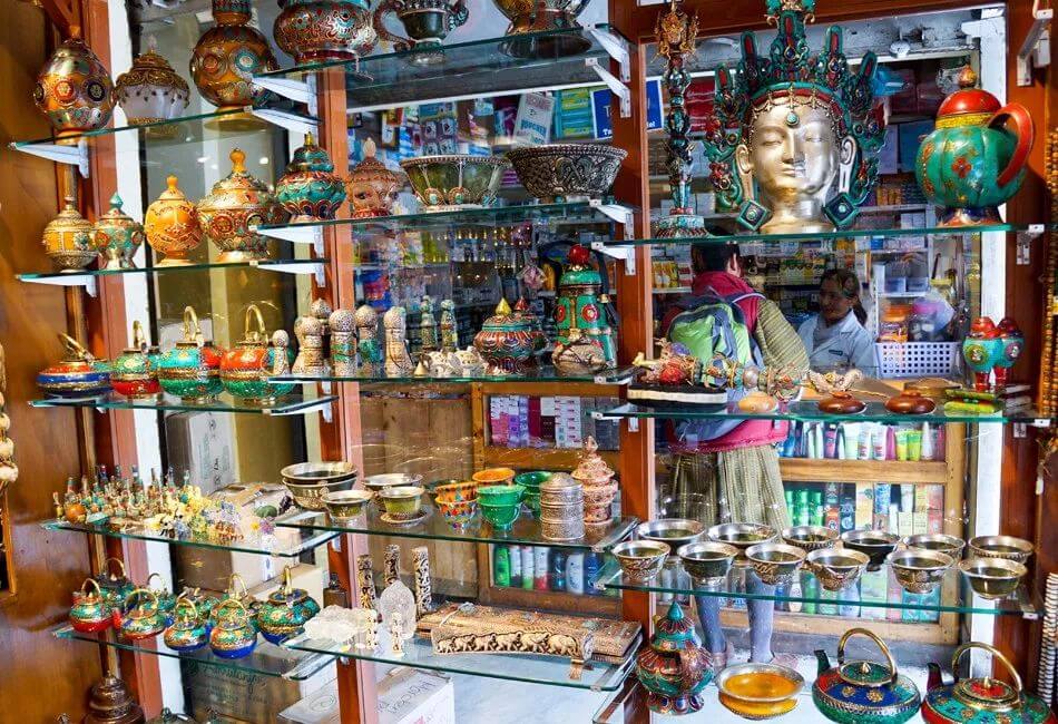 該圖片展示了一間不丹紀念品店的展示櫃,擺滿了精緻的手工藝品,包括金屬雕刻、佛像以及裝飾性器皿,展現了當地豐富的手工製品文化。