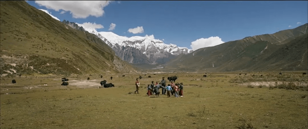 這張圖片中，學生們與老師在廣闊的草原上學習，背景是連綿的山脈和雪峰。這種戶外教學的場景展現了不丹教育的獨特氛圍，學生們在大自然的擁抱中學習成長。