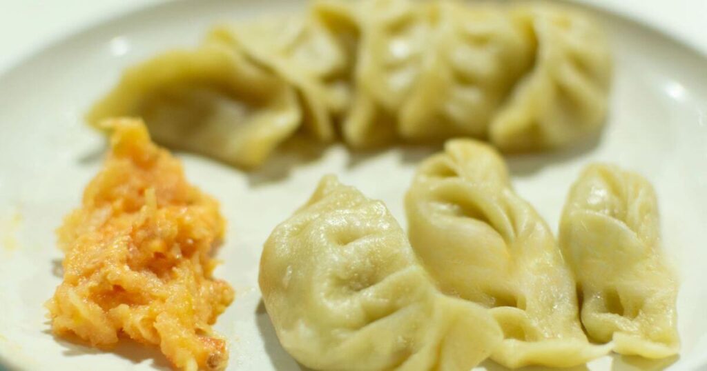 這盤Momos是用肉餡和蔬菜製作的餃子，配有醬料，皮薄餡多，帶有溫暖的手工風味，是不丹的受歡迎小吃。