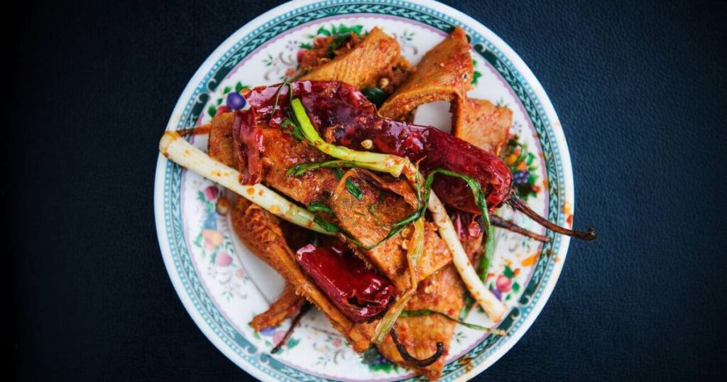 這道料理以切片豬肉、辣椒和蔬菜為主料，經過翻炒後香氣四溢，辣味十足，色澤誘人，是不丹的經典家常菜。